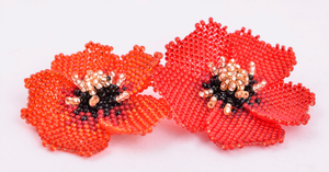 Two red handmade beaded poppies against a white background.